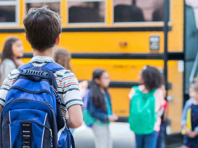 Young boy waits to load school bus